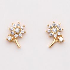 two pairs of gold tone earrings with white stones on each earring side by side