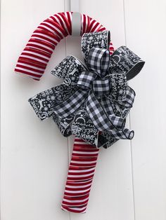 a red and white striped christmas wreath hanging on the side of a door with black and white stripped stockings