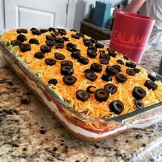 a casserole dish with cheese and black olives on it, ready to be eaten