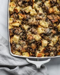 a casserole dish filled with meat and cheese on top of a white cloth