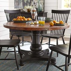 a wooden table with chairs around it and oranges on the table next to it