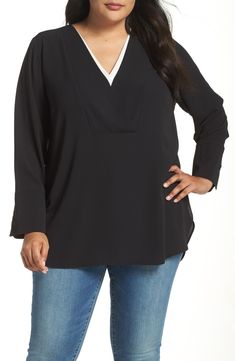 a woman in jeans and a black top is standing with her hands on her hips