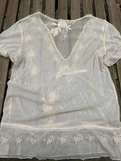 This antique cream blouse is made of a light see through netting fabric with pretty embroidery. It has short sleeves and a dropped waist with ribbon ties for adjustment.  It has no fastenings and is loose enough to put on over the head. The brand is CCDK, and it is marked size 38, which is a UK Size 12. It is in excellent vintage condition. Short Sleeve Delicate Lace Tops For Summer, Summer Lace Mesh Top, Delicate Lace Short Sleeve Top For Summer, Delicate Lace Short Sleeve Summer Tops, Floral Embroidery Lace Top With Short Sleeves, Cream Short Sleeve Lace Top For Summer, Short Sleeve Lace Top With Lace Trim For Summer, Summer Mesh Top With Lace Trim, Cream Lace Top With Short Sleeves For Summer