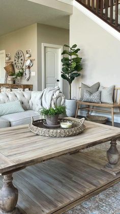 a living room filled with furniture and a wooden table in front of a stair case