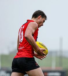 a man holding a yellow and black ball in his right hand while standing on a field