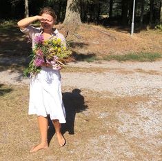 a woman standing in front of a tree holding a bunch of flowers on her head