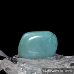 a green rock sitting on top of some ice crystals in front of a black background