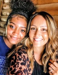 two women sitting next to each other smiling at the camera with their arms around one another