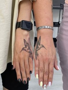 two women with matching tattoos on their hands holding each other's hands and looking at the camera