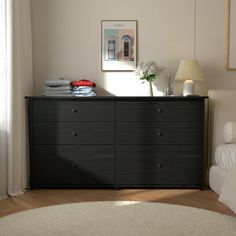 a bedroom with a bed, dresser and pictures on the wall