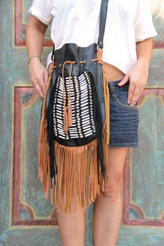 Boho style fringed leather bag black with tan fringes and white bone choker Bone bead choker attached as decoration Fully lined inside with one pocket. strap can be adjusted to several lengths. Material: leather, cow bones 26 cm wide,39 cm long. total long include leather fringes 60 cm Best finishing quality Please note that our products are handmade with some natural materials. For this reason the used materials such as leather and feathers may have slight variations in color. Please do not for Black Bohemian Shoulder Bag With Tassels, Black Bohemian Bag With Fringe, Bohemian Leather Hobo Bag With Tassels, Bohemian Brown Bag With Beaded Fringe, Bohemian Festival Bags With Beaded Fringe, Black Bohemian Hobo Bag, Black Fringed Shoulder Bag For Festival, Black Fringe Shoulder Bag For Festival, Bohemian Brown Bucket Bag With Tassels