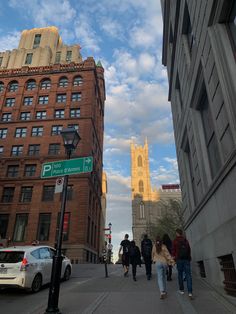 people walking down the street in front of some tall buildings with towers on each side