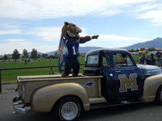 an old pickup truck with a mascot on the back