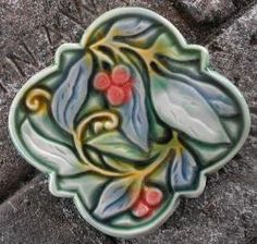 a decorative ceramic object sitting on top of a stone slab with leaves and berries painted on it