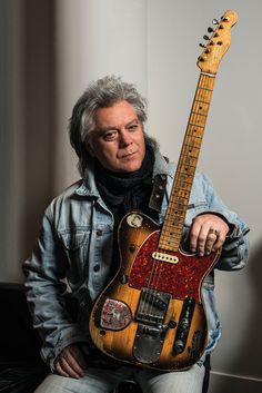 a man is holding an electric guitar in his hand and posing for the camera with it's neck up