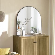 a living room with a couch, mirror and vases on the side of it