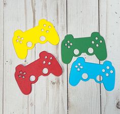 four different colored video game controllers on a white wooden surface with holes in the middle