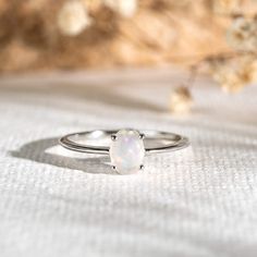 a white opal ring sitting on top of a table next to some dried flowers