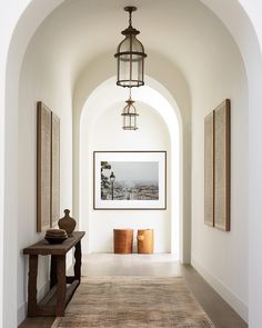 a hallway with an archway leading to the dining room and living room, along with two vases on either side