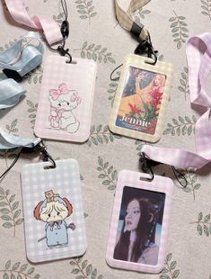 four tags with cartoon characters on them sitting on top of a table covered in ribbon