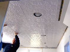 a man is painting the ceiling in an empty room with white walls and ceilings,