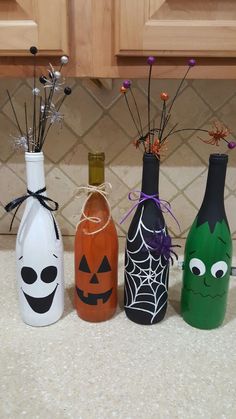 three bottles with halloween decorations in them on a kitchen counter