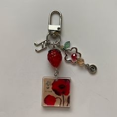 a keychain with a red flower on it and a heart charm attached to it