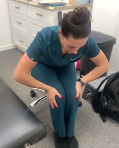 a woman sitting in an office chair with her hand on her knee and looking down