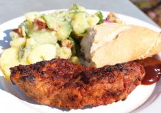 a white plate topped with meat, potatoes and salad