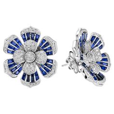 Shine bright with these stunning diamond and sapphire earrings. The earrings features 146 round cut diamonds and 96 French cut blue sapphires. These magnificent and timeless earrings would add a touch of grace and elegance to any occasion! Earrings Information Style: Art Deco Metal: 18K White Gold Width: 23 mm. Length: 26 mm. Weight: 17.70 g. (approx. in total) Backing: Push Back Gemstones I Type: Diamond Shape: Round Average Color: H Average Clarity: SI Size: 1 - 1.3 mm. Number: 146 Weight: 1.0 Branded Earrings, Sapphire Diamond Earrings, Art Deco Metal, Diamond Tops, Timeless Earrings, Sapphire And Diamond Earrings, Floral Studs, Earring Box, Jewellery Sketches