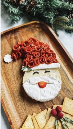 a wooden tray with crackers, crackers and cheese in the shape of santa claus