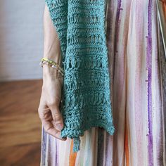 the woman is wearing a green crocheted shawl and holding onto her purse