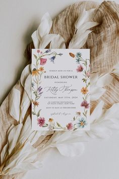 an elegant floral bridal shower card on top of some feathers