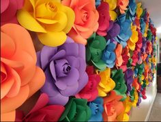 colorful paper flowers are arranged on the wall