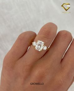 a woman's hand with a three stone diamond ring on top of her finger