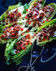 lettuce with bacon and ranch dressing on it sitting on a plate next to scissors