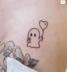 a woman's stomach with a ghost holding a heart balloon tattoo on her left side