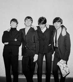 the beatles are posing for a photo in their suits and ties, with one holding his arm around another man's shoulder