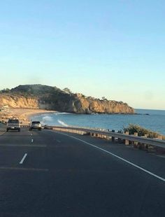 cars driving down the road next to the ocean