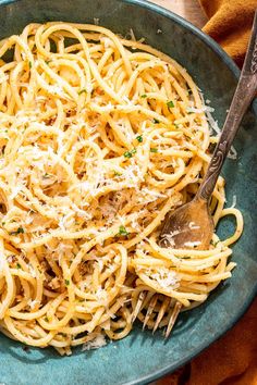 a blue bowl filled with pasta and parmesan cheese