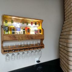 a wall mounted wine glass rack with bottles and glasses on the bottom shelf in front of a brick wall