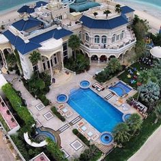 an aerial view of a mansion with a swimming pool in the foreground and beachfront