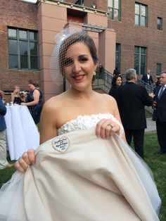 a woman in a wedding dress is holding her veil over her shoulder and smiling at the camera