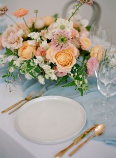 an arrangement of flowers on a table with silverware