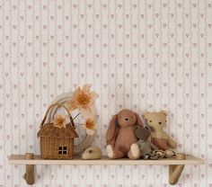 two teddy bears sitting on a shelf in front of a wallpapered wall with flowers