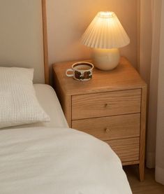 a nightstand with a lamp on it next to a bed