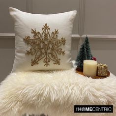 a white pillow sitting on top of a fur covered chair next to a christmas tree