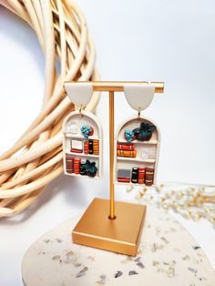 a pair of earrings with books on them sitting on top of a table next to a wicker basket