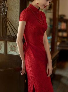 a woman in a red dress standing next to a door with her hands on her hips