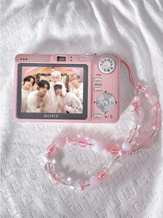 a pink camera sitting on top of a white blanket